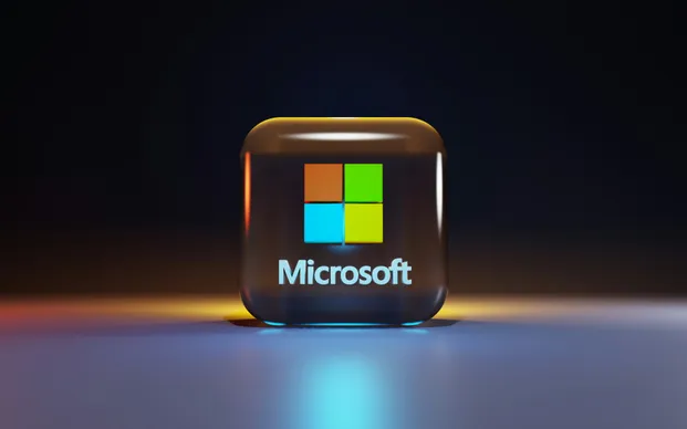 Microsoft logo displayed on a cube with blue and yellow light effects against a dark background.